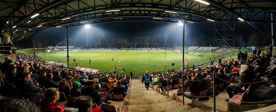 Estadio iluminado con aficionados viendo un partido nocturno